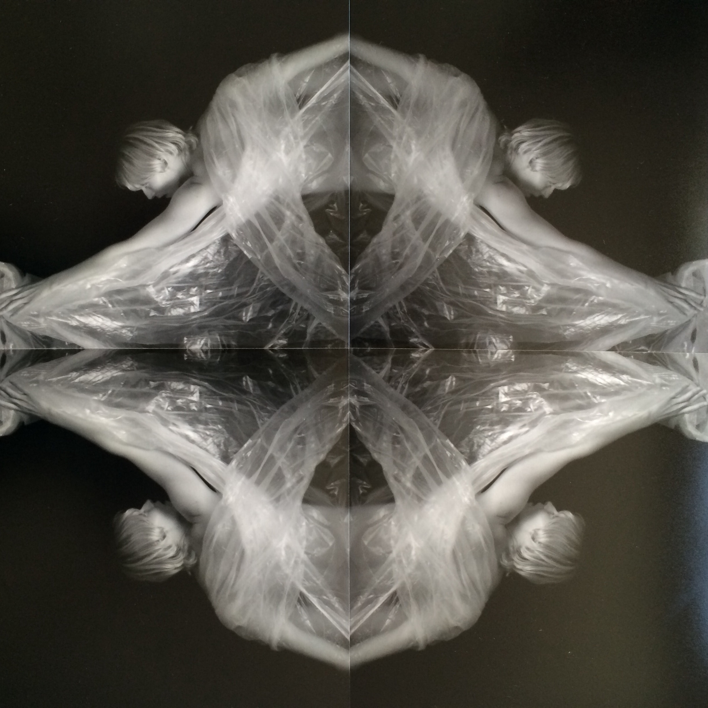 Four reflected views of a figure and flowing translucent material forming a symmetrical composition