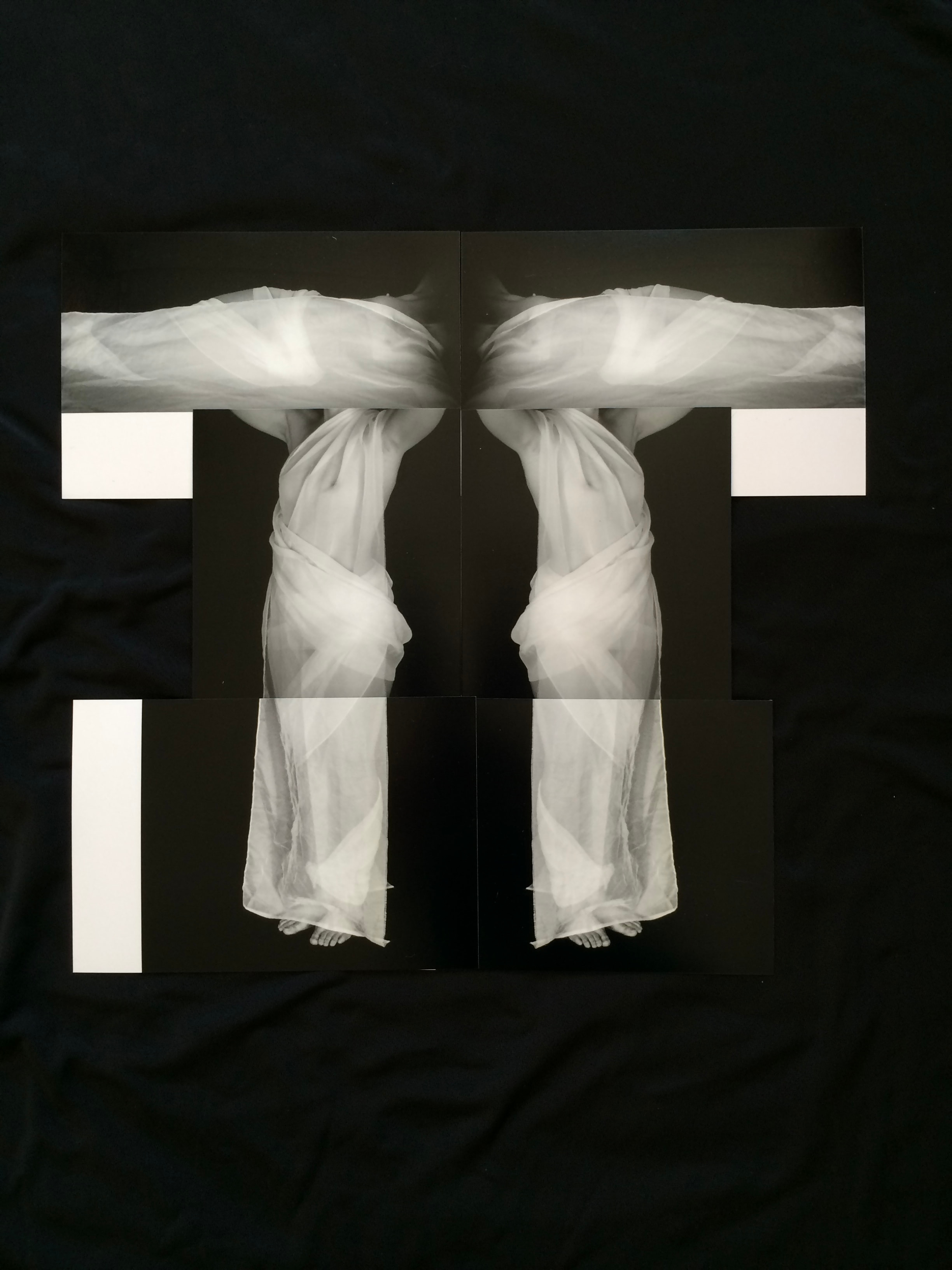 Mirrored pale draped figures arranged across rectangular panels against black