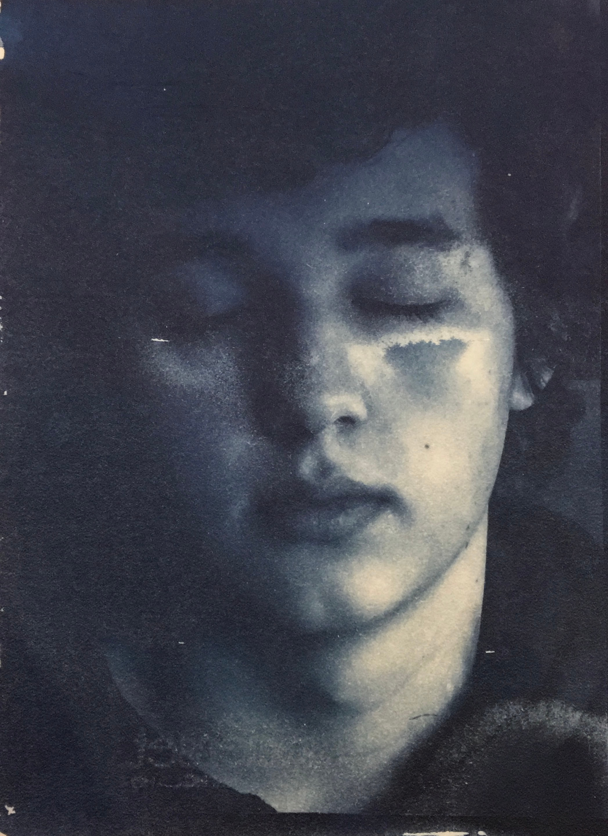 Blue-toned close-up portrait with closed eyes and one side of the face in shadow