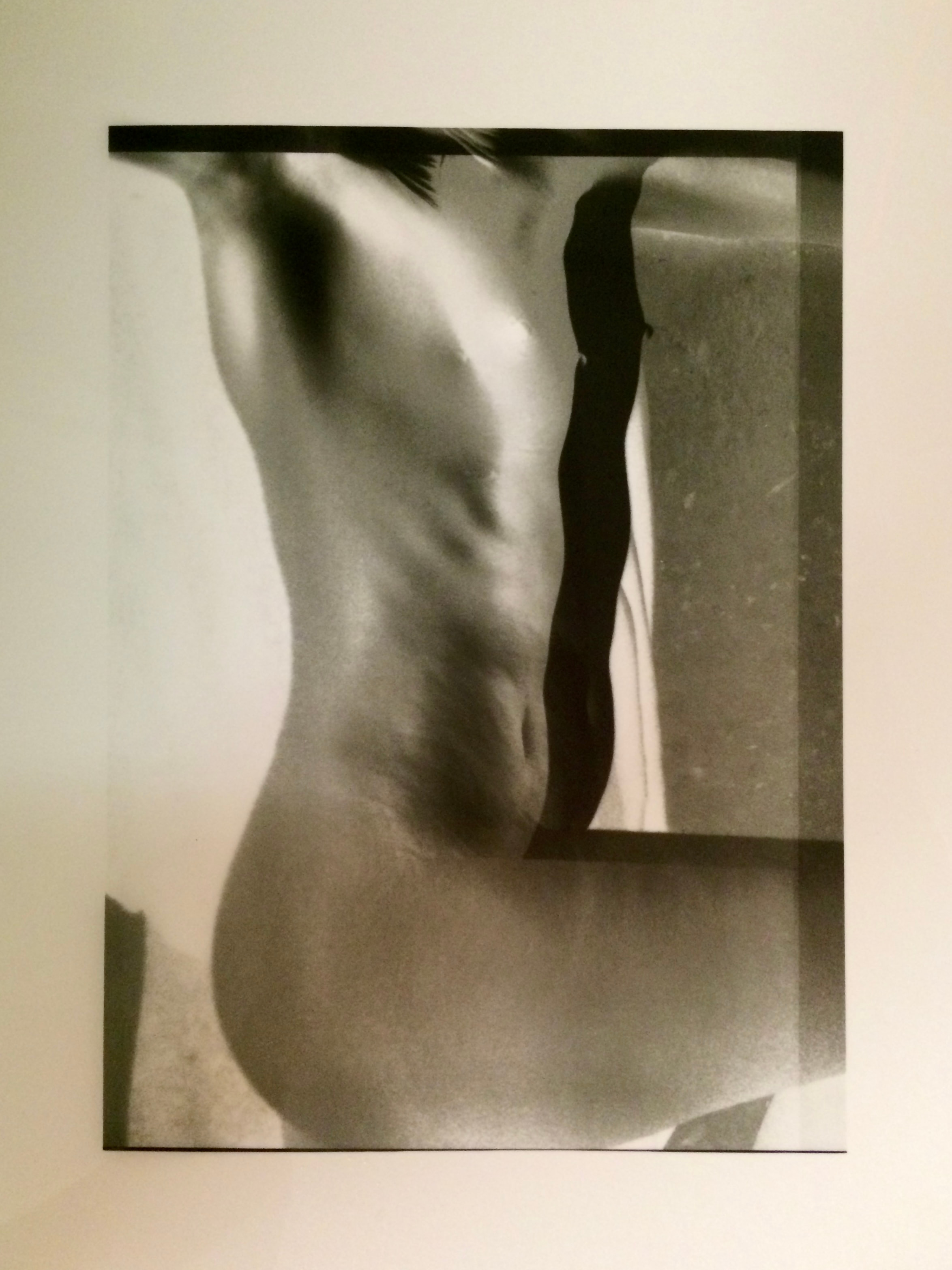A monochrome print showing a cropped torso with light and shadow across the body