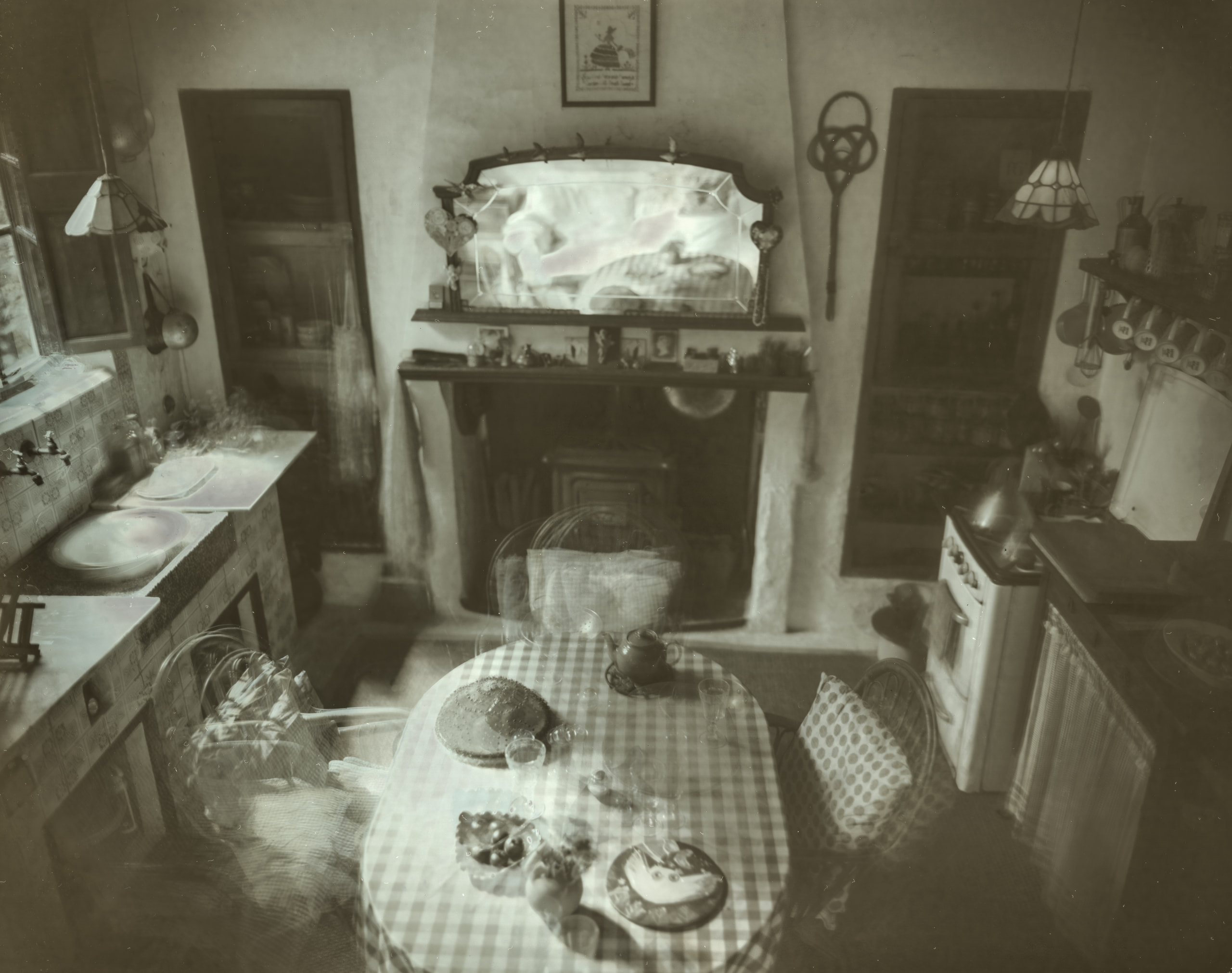 Room with a fireplace, mirror and round table, with overlapping translucent chairs and table settings
