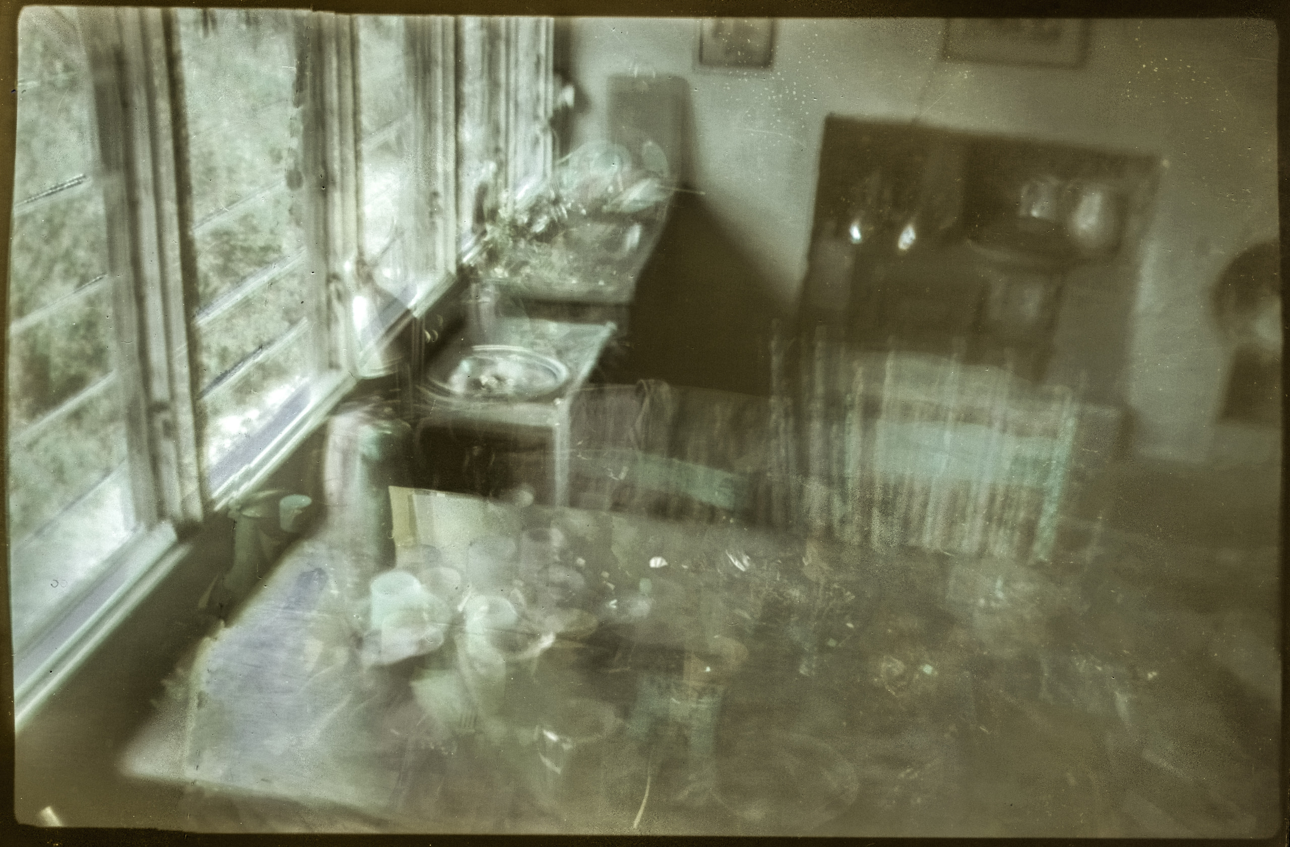 Interior with a table beside tall windows and overlapping translucent chairs and objects